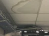 A stained ceiling tile indicates a water leak directly above computer equipment racks in an office setting.